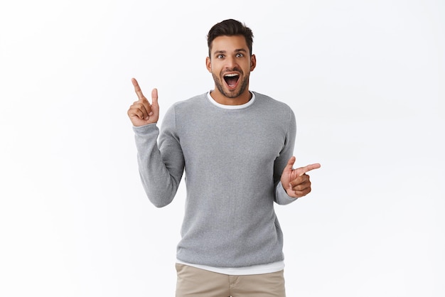 Cheerful excited guy spot interesting promo and share with us Smiling handsome man pointing sideways as shopping in store with variety choices open mouth fascinated look amused and happy