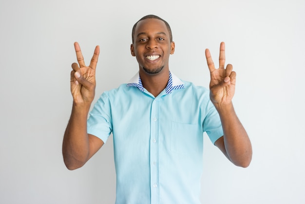 Cheerful excited handsome African man showing peace signs and looking at camera.