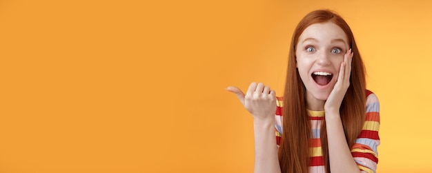 Free photo cheerful excited impressed talkative girl pointing astonished thumb left drop jaw smiling broadly