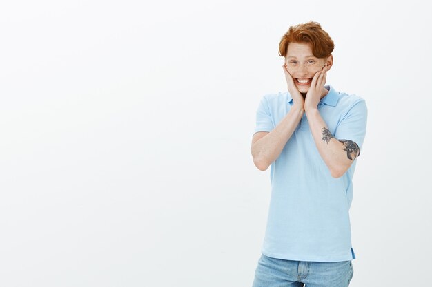 Cheerful and excited redhead man blushing and looking happy, smiling amused