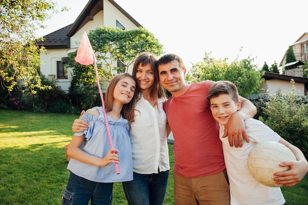 Cheerful family having picnic standing together on green nature in park