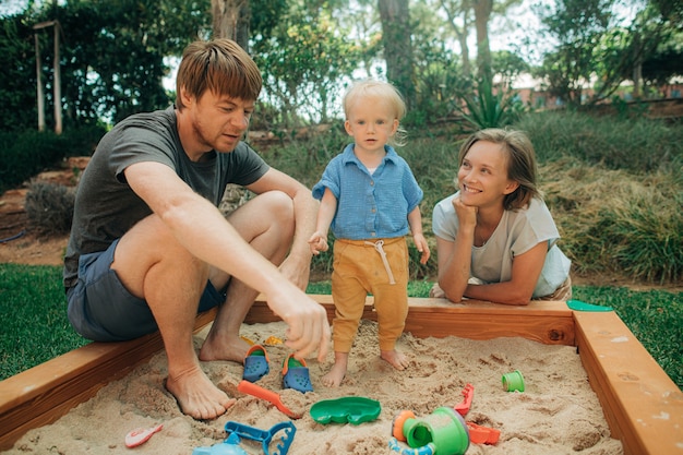 Cheerful family playing together in sandpit