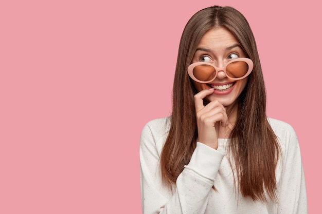 Foto gratuita adolescente grazioso alla moda allegro con capelli lunghi scuri, morde il dito anteriore