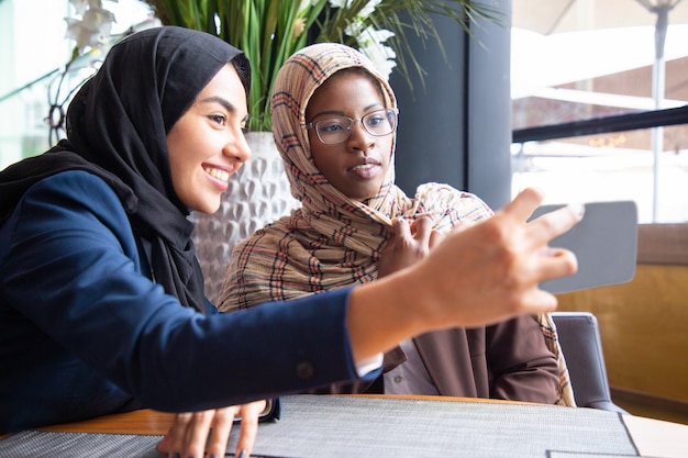 Free photo cheerful female business colleagues taking selfie