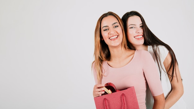 Cheerful female couple holding paper bag