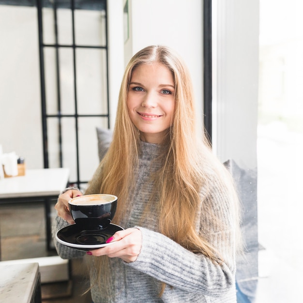 Cheerful female holding cup with saucer