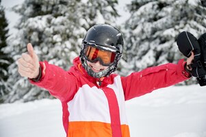 Foto gratuita sciatore femminile allegro che sta nella foresta della montagna di inverno