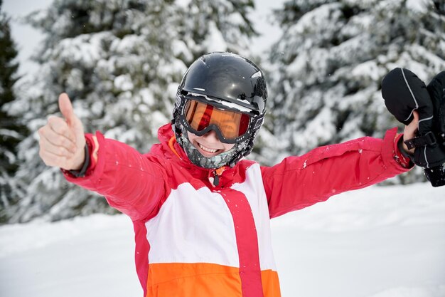 Cheerful female skier standing in winter mountain forest