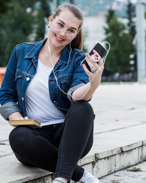 Cheerful female taking selfie sitting in park