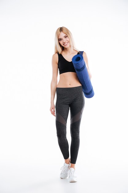 Cheerful fitness lady holding sports rug