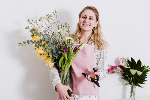 Cheerful florist with pruner and vase