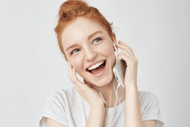 Cheerful foxy woman rejoicing listening music in headphones smiling.