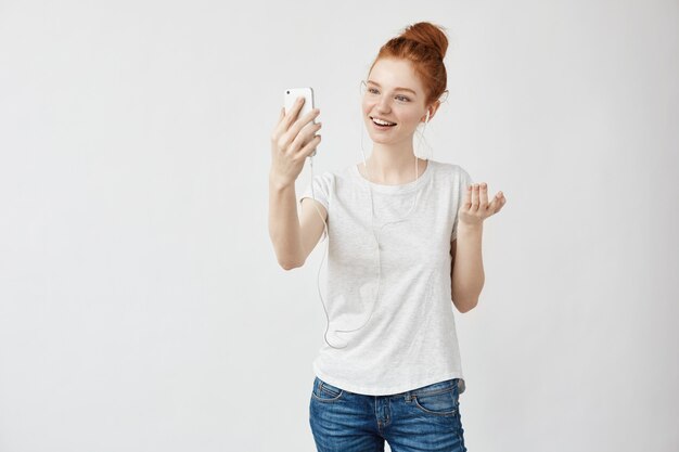 Cheerful foxy woman smiling talking on phone in headphones.