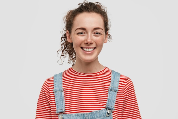 Free photo cheerful freckled young woman posing against the white wall