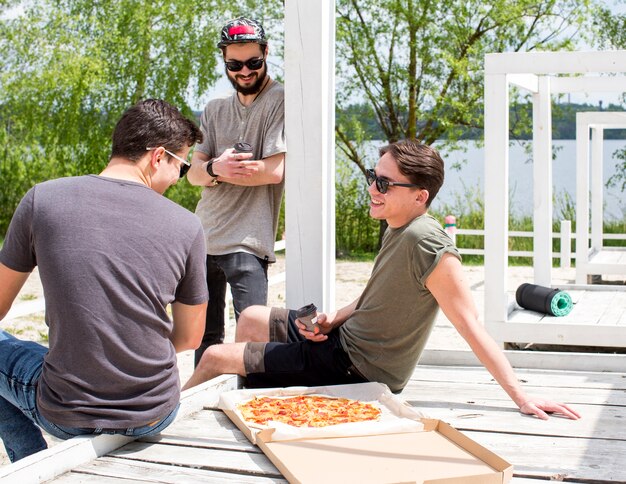 Cheerful friends chatting on picnic by lake