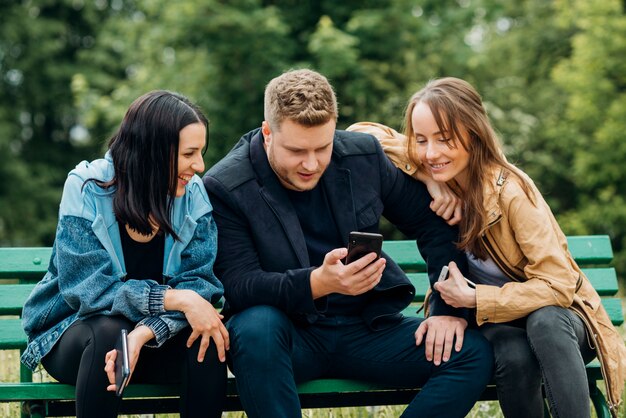 Cheerful friends chilling on bench in park