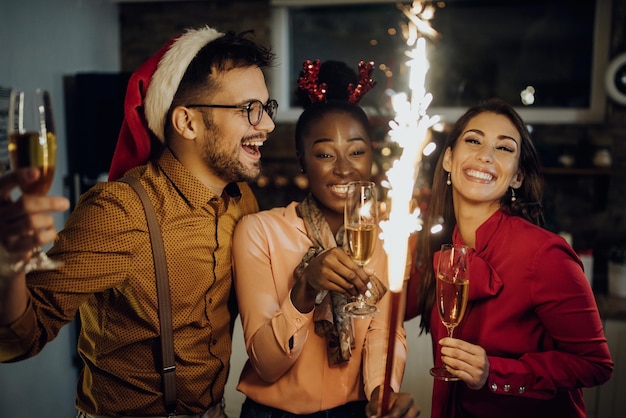 Веселые друзья пьют шампанское и веселятся в новогоднюю ночь дома