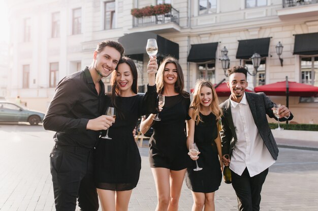 Веселые друзья пьют шампанское на вечеринке на открытом воздухе