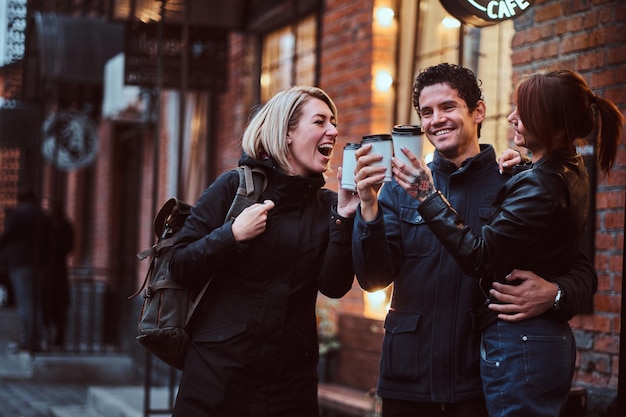 Cheerful friends toasting coffee near a cafe: Free stock photo download