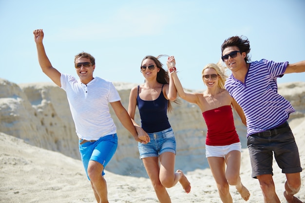 Cheerful friends running in the sand