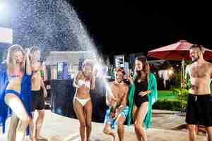 Free photo cheerful friends smiling, rejoicing, resting at party near swimming pool