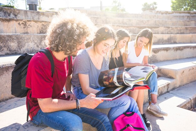 Cheerful friends studying on street stairs