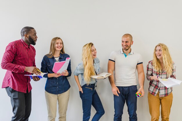 Cheerful friends talking with notepads in hands