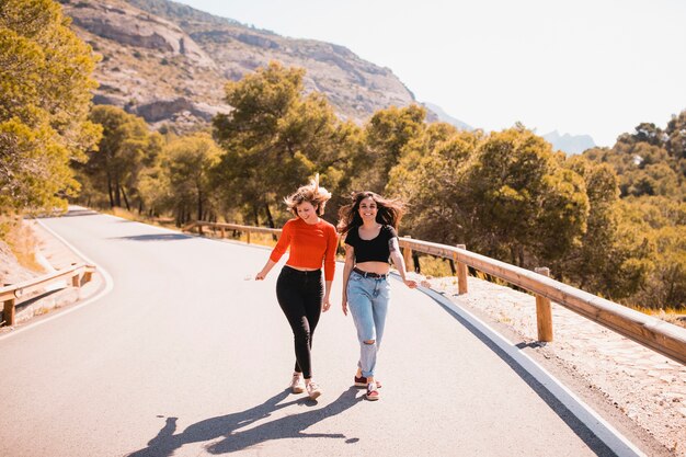 Cheerful friends walking along countryside road