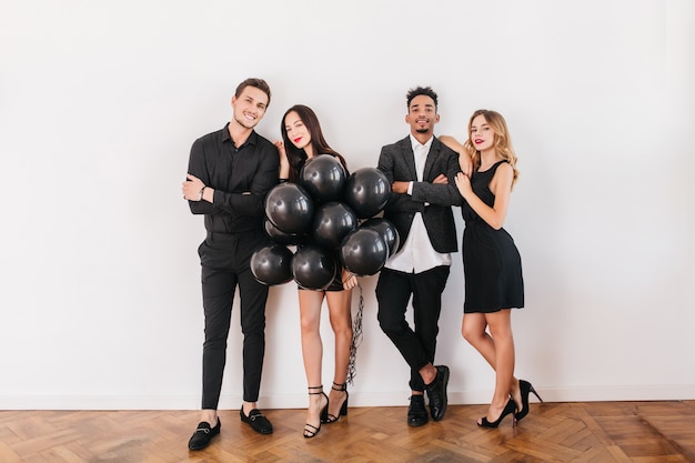 Cheerful friends with black balloons during home party