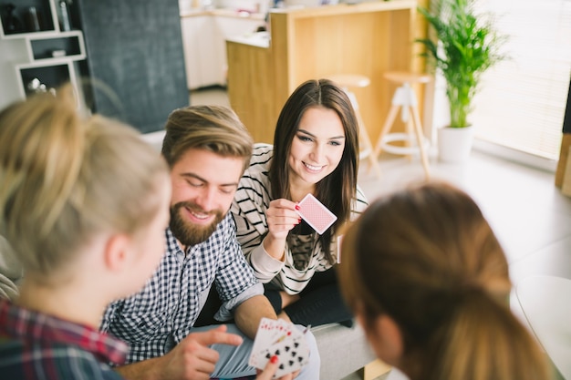 Cheerful friends with playing cards having fun