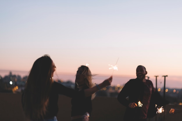 Cheerful friends with sparklers at night