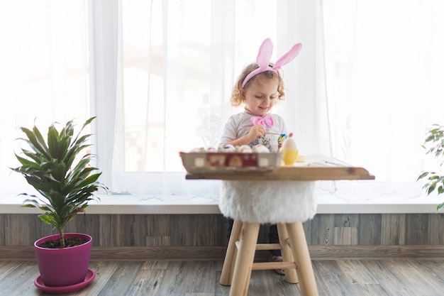 Cheerful girl coloring eggs