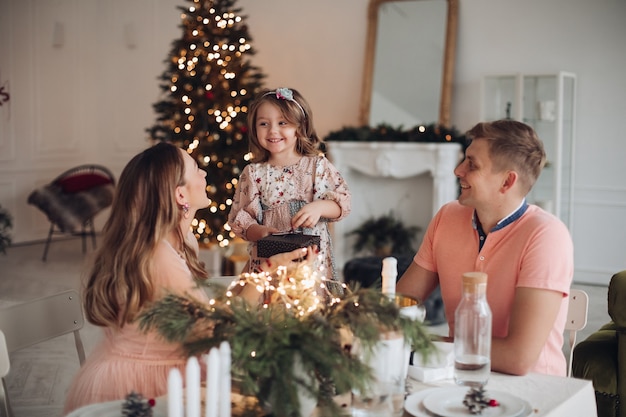 Free photo cheerful girl getting christmas presents from parents