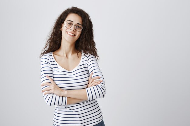 Cheerful girl in glasses smiling, cross arms chest delighted