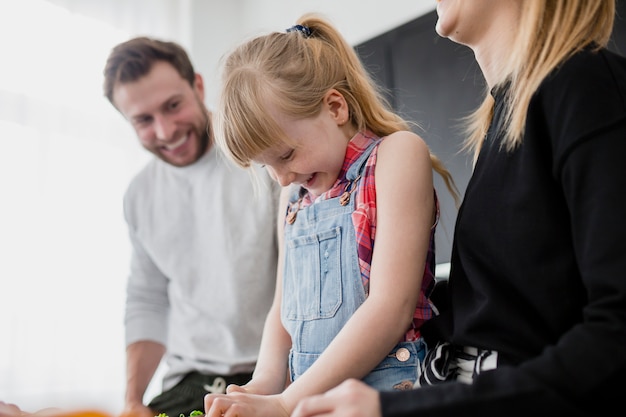 Cheerful girl helping parents with cooking