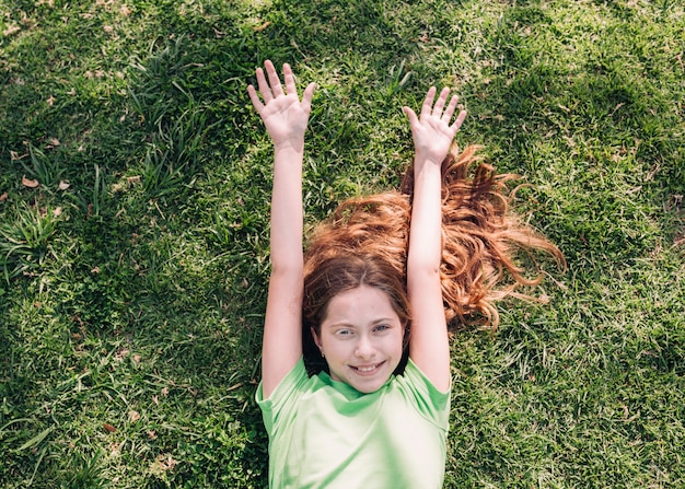 Cheerful girl lying on grass in sunlight