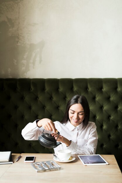 カフェテリアでお茶を注ぐ朗らかな女の子