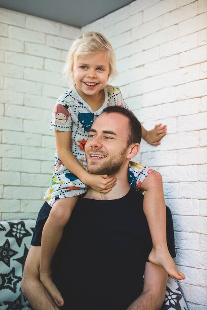 Cheerful girl on the shoulders of her father