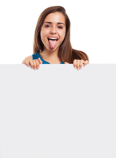 Cheerful girl showing her tongue and holding an empty sign