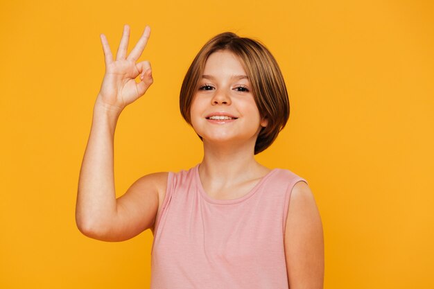 Cheerful girl showing ok gesture isolated