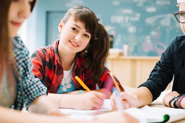 Cheerful girl sitting with classmates at table