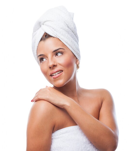 Cheerful girl in towel with hand over shoulder
