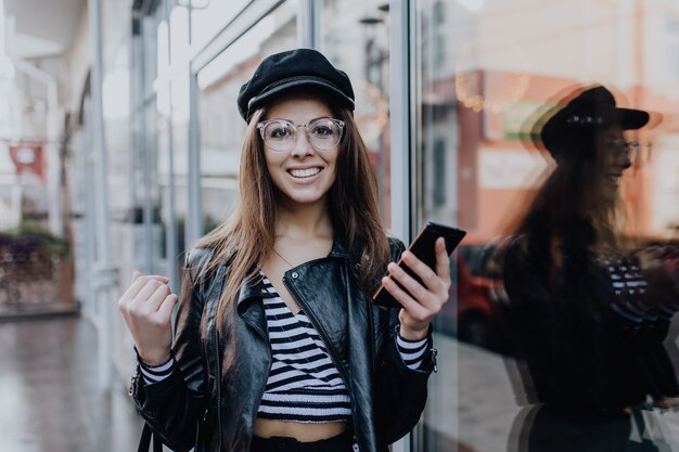 Cheerful girl walks on the street in black leather jacket after rain