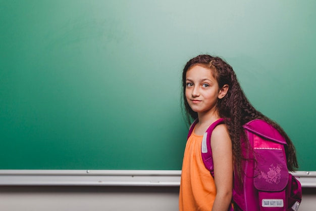 Cheerful girl with backpack in class