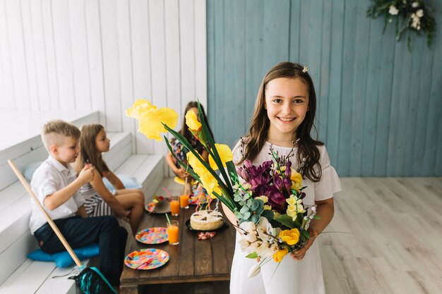 Cheerful girl with bouquet on birthday party