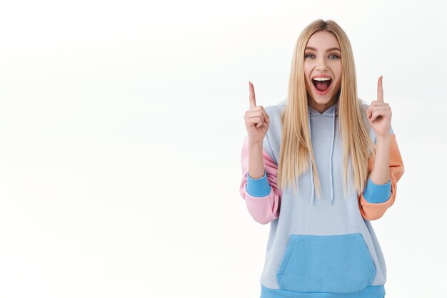 Cheerful good-looking blond girl in hoodie found best offer, discounts on shopping site, online promo offer, pointing fingers up