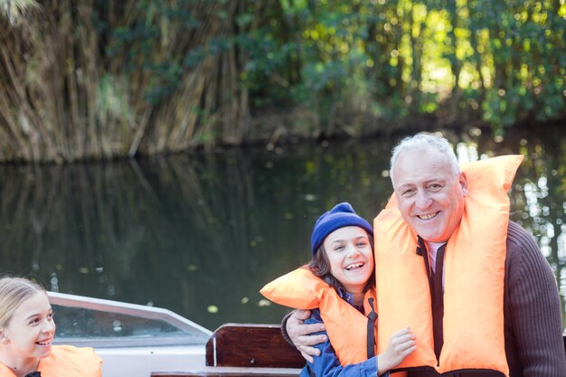 Cheerful grandfather and grandson dressed in orange life vests