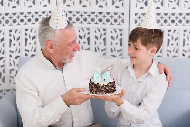 촛불로 맛있는 케이크를 잡고 서로를보고 명랑 할아버지와 손자