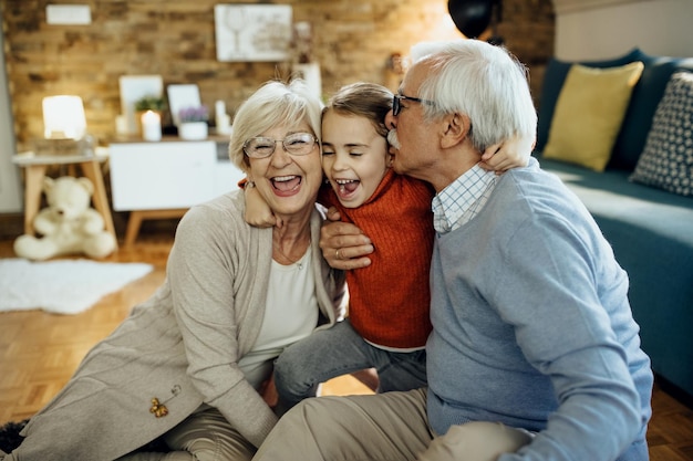 Cheerful grandparents and granddaughter having fun together at home
