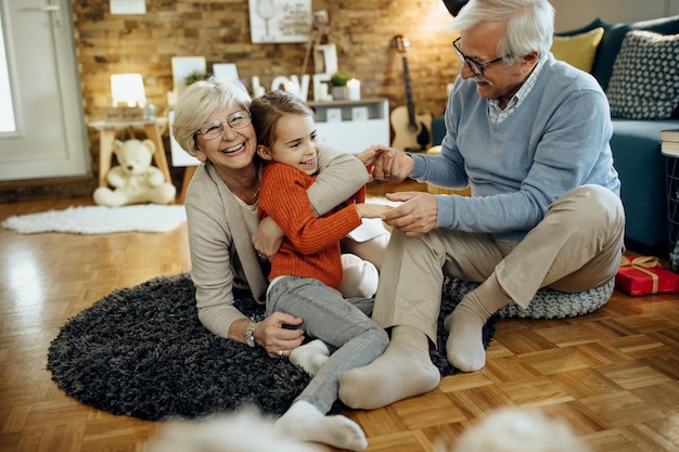 Cheerful grandparents having fun with their granddaughter at home